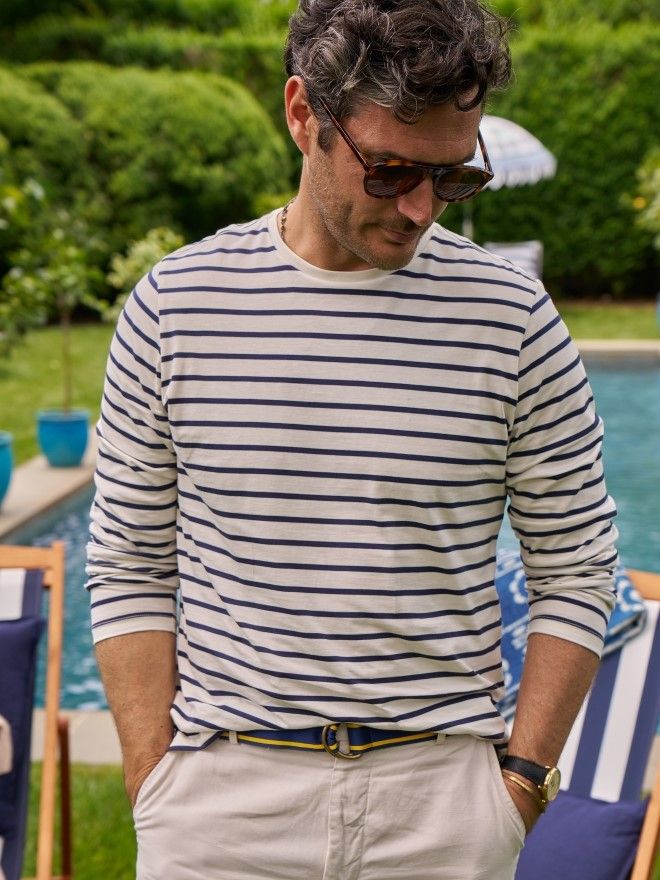 Man wearing a cream and navy striped crewneck tee with light stone colored chino pants