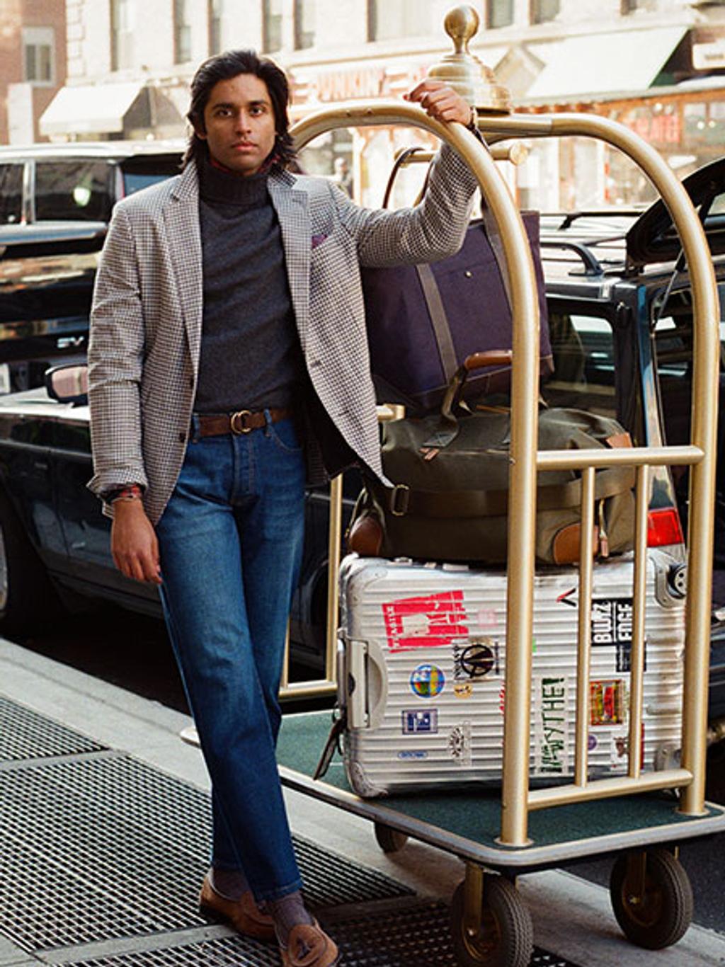 Model wearing a dark turtleneck, blue denim, and a patterned sports coat.