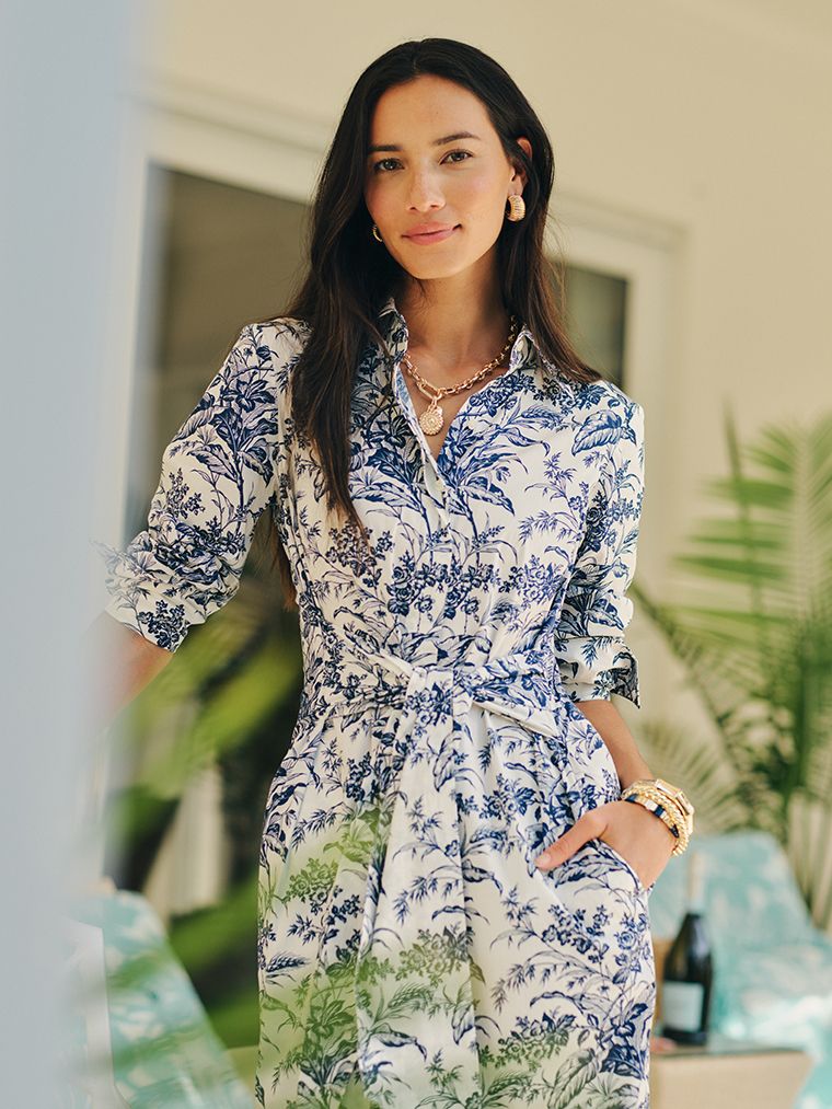 women standing outside in a blue toile dress with hand in pocket