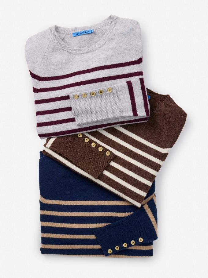 laydown against white seamless background of womens stripe cashmere crewneck sweaters in various colors