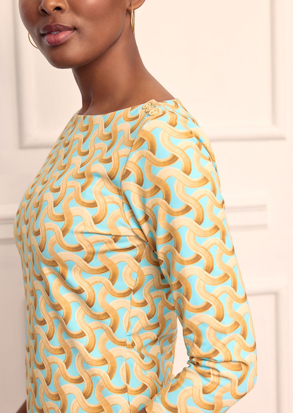 Close up shot of a model wearing a geometric patterned top that is aqua and brown.