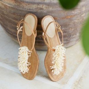 neutral leather and white beaded sandals standing upright in front of neutral backdrop