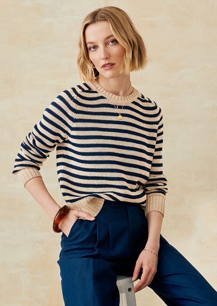 Woman sitting in a striped linen sweater and navy linen pants. 
