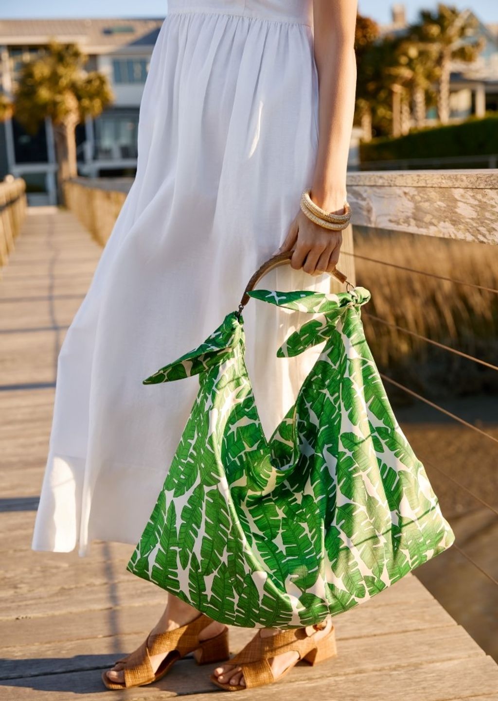 cropped image of women in white dress holding green palm printed oversize scarf tote