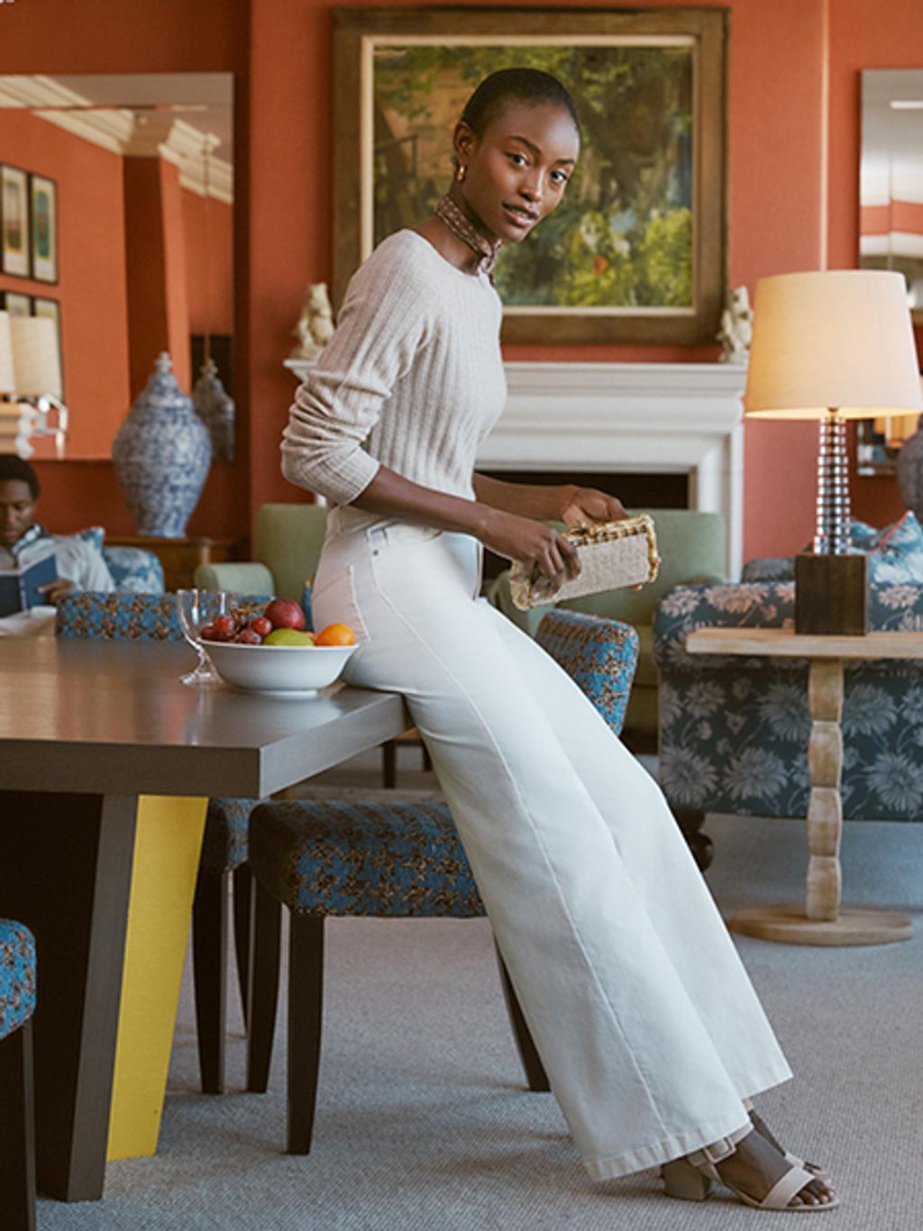 Model wearing cashmere sweater with wide leg jeans and suede block heels.