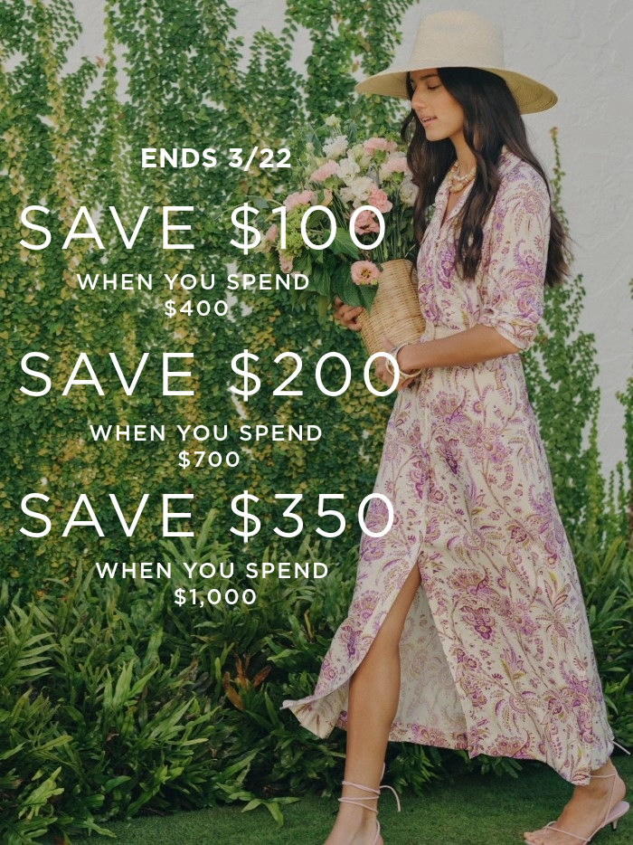 woman wearing long flowy paisley dress walking outside and holding bouquet of flowers