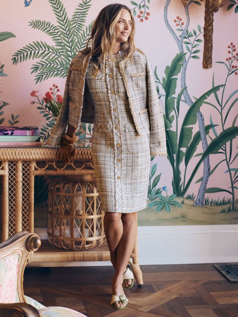 woman standing in a room with pink walls and palm wallpaper wearing tan tweed matching sheath dress and jacket