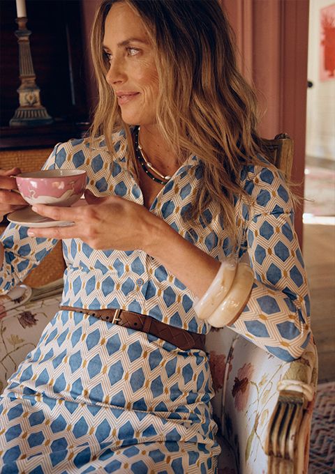 woman seated inside wearing white and teal geo printed shirtdress