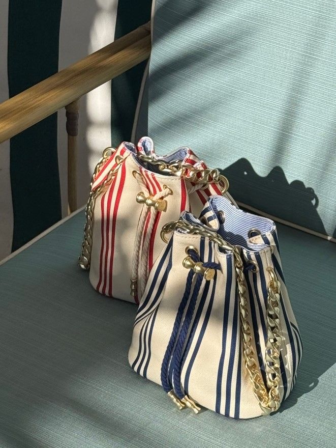 Two canvas bucket bags, one red-and-white striped and one navy-and-white striped, with gold chain straps.