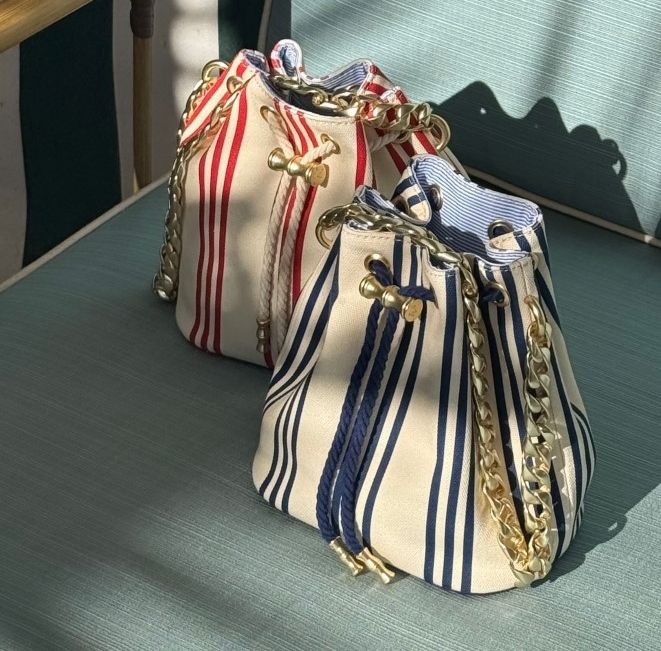 Two canvas bucket bags, one red-and-white striped and one navy-and-white striped, with gold chain straps.