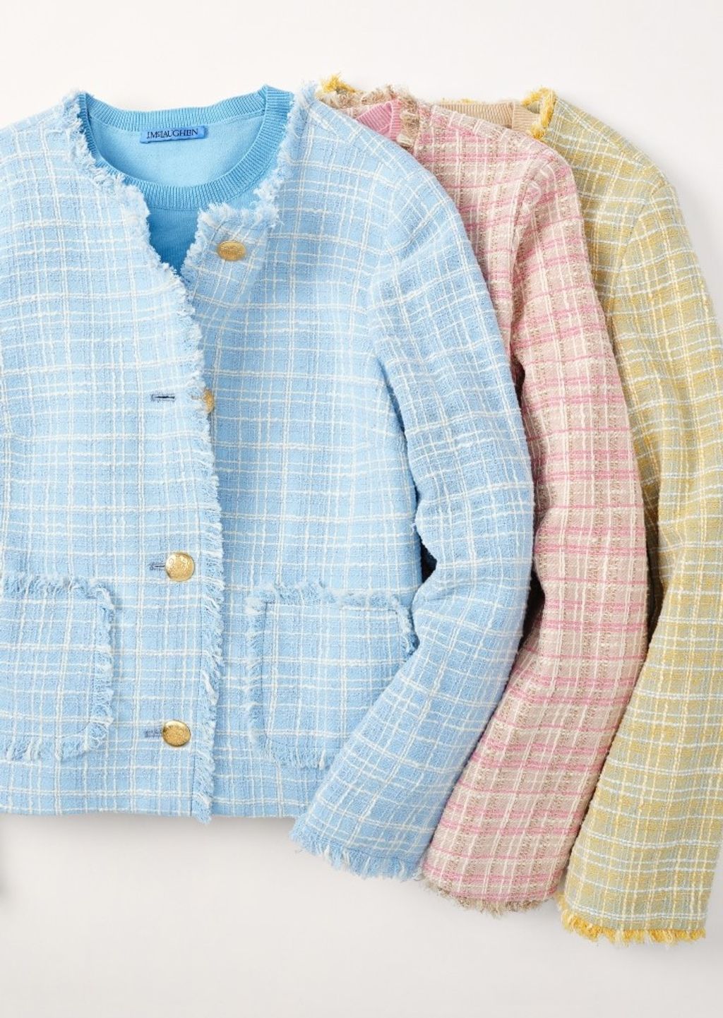 Three pastel plaid blazers with gold buttons and fringed edges, in blue, pink, and yellow.