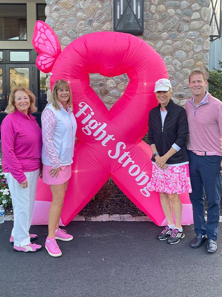 Participants at a breast cancer awareness event posing with an inflatable 'Fight Strong' ribbon display
