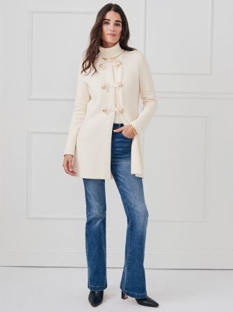 woman wearing long cream knit cardigan with medium wash bootcut jeans