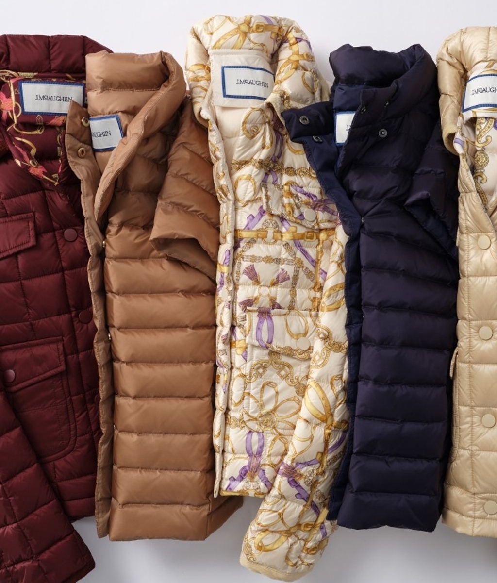 A row of five women's puffer jackets and vests in various colors and patterns.