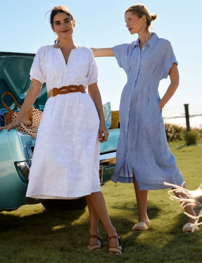 two women standing outside next to a car, one wearing white pull sleeve eyelet midi dress, the other a blue and white hairline stripe linen shirtdress