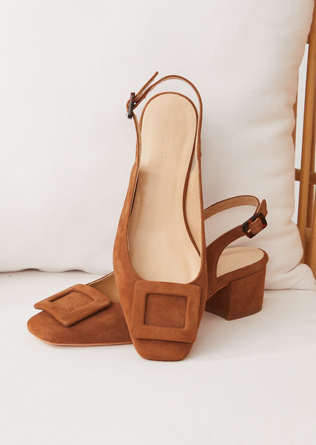 brown suede low heel with buckle posed on chair