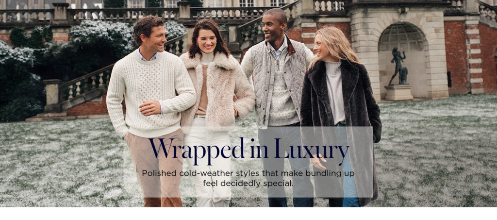 Four smiling people in elegant winter fashion, including faux fur coats and sweaters, walk on snowy ground in front of a grand building. Overlay text: "Wrapped in Luxury. Polished cold-weather styles that make bundling up feel decidedly special."