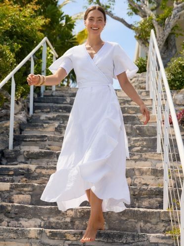 woman walking down stairs smiling in white flutter sleeve dress