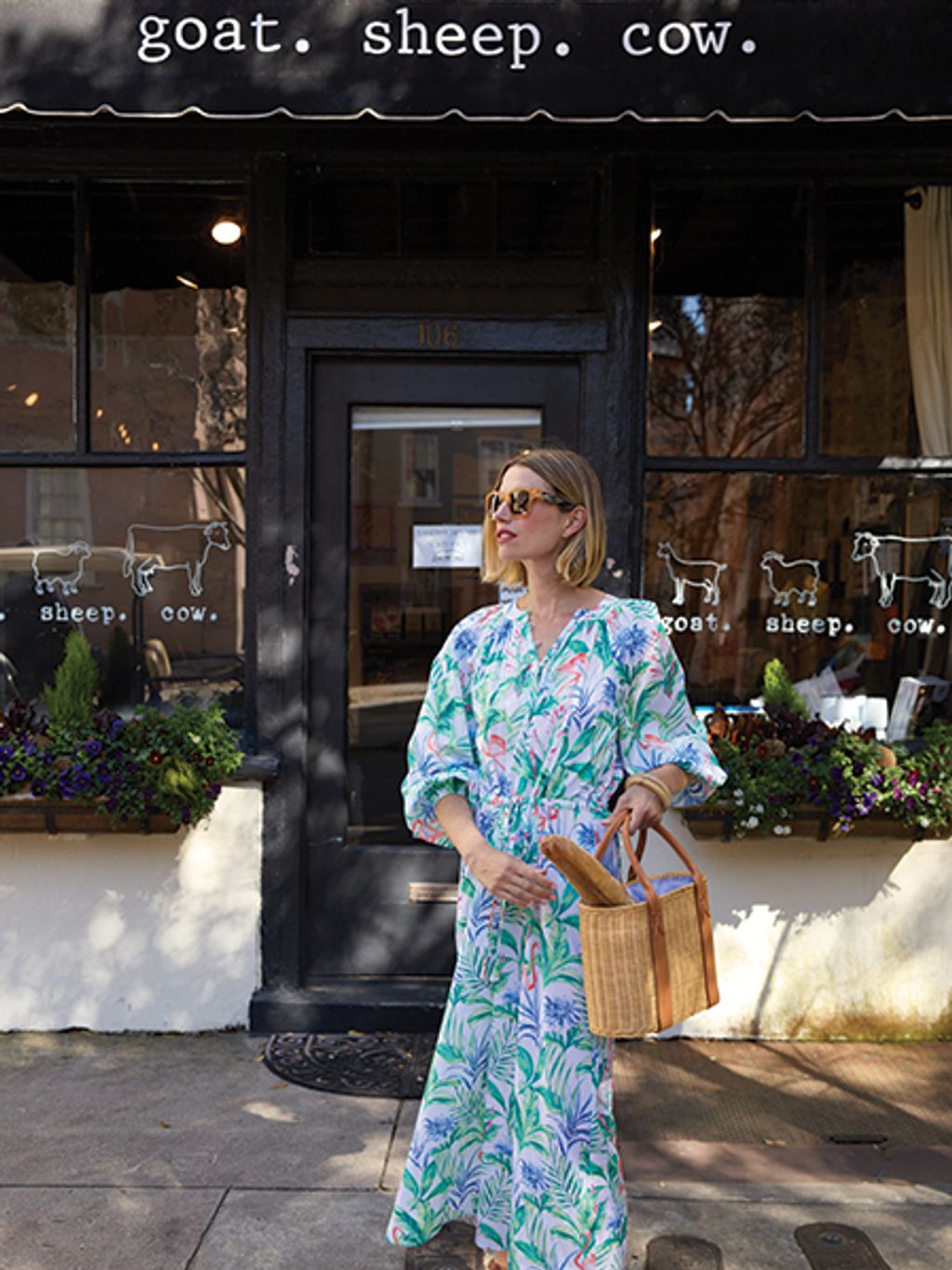 Model in tropical-print dress in front of goat.sheep.cow cheese shop