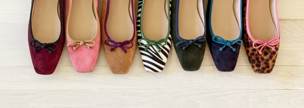 Seven colorful ballet flats in a row, including patterned and solid colors.