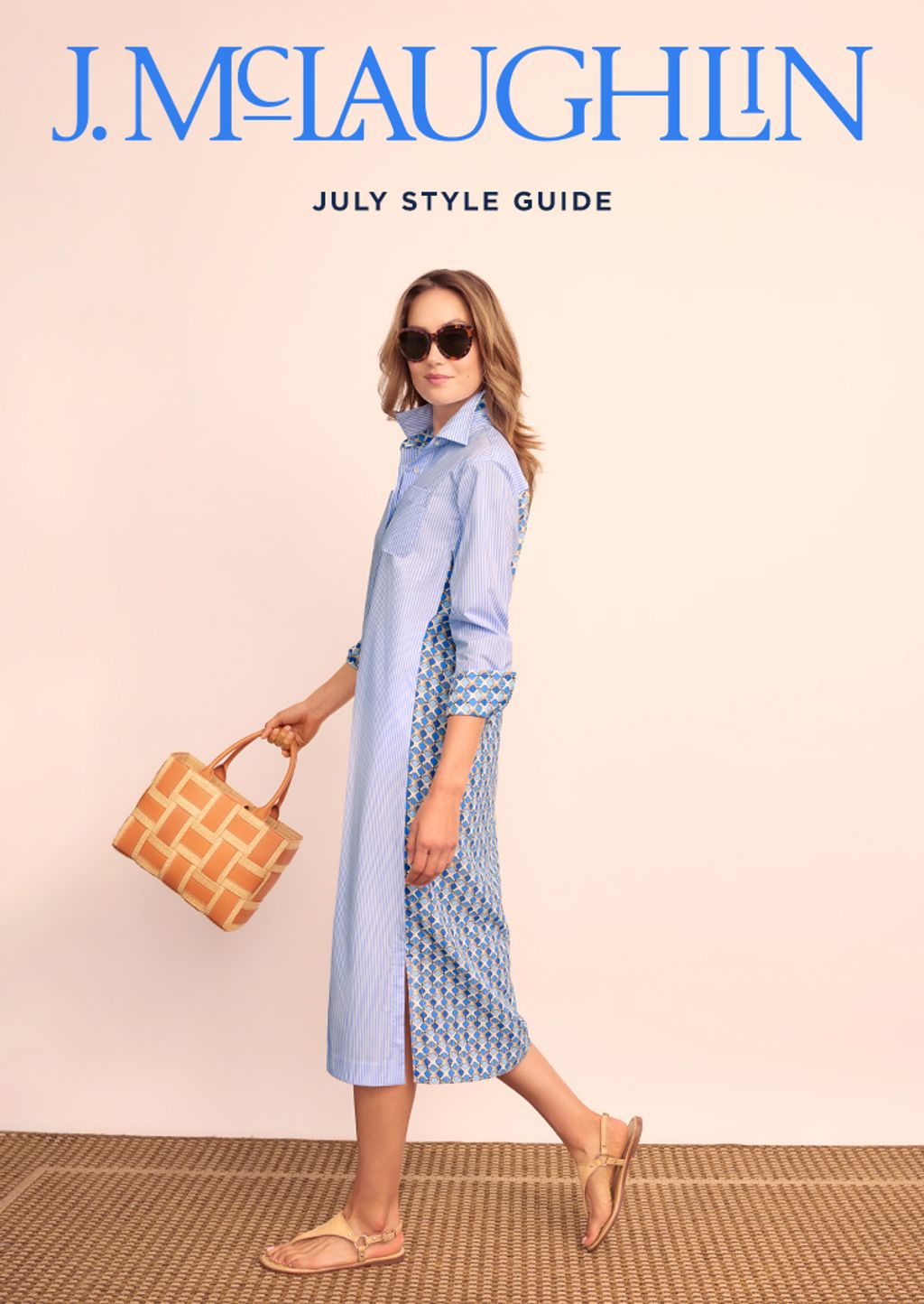 Model wearing back printed shirt dress carrying wicker handbag. 