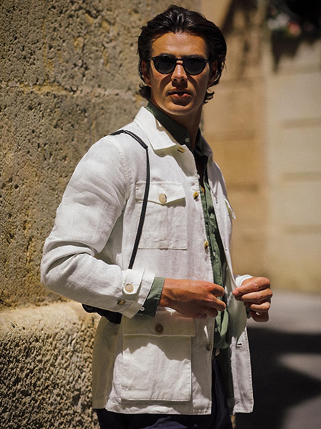 Man wearing sunglasses, a white denim jacket, and dark denim jeans.