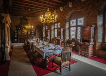 Festlich gedeckter Speisesaal der Reichsburg Cochem mit Kronleuchtern und holzvertäfelten Wänden