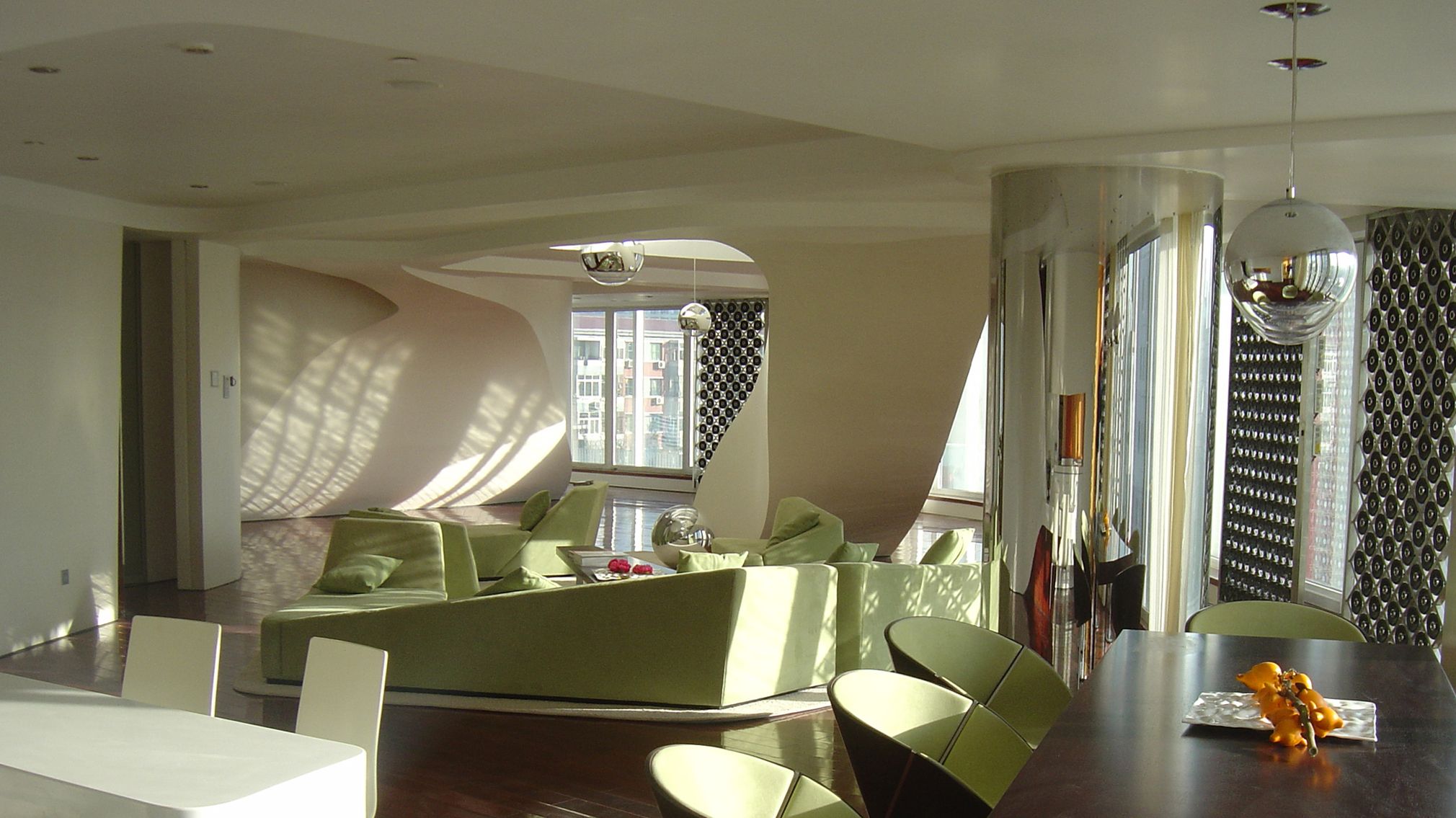 Semi-transparent spatial dividers, carved in traditional Chinese lattice patterns, can be used to quickly partition off the space for intimate family functions or to open it up for entertaining. The interior design of a duplex unit in Shoulu Huayan Towers in Beijing, China, as a model apartment for the complex features a master bedroom on the gallery level and a representative living area and lounge along the façade, ending in a private office.