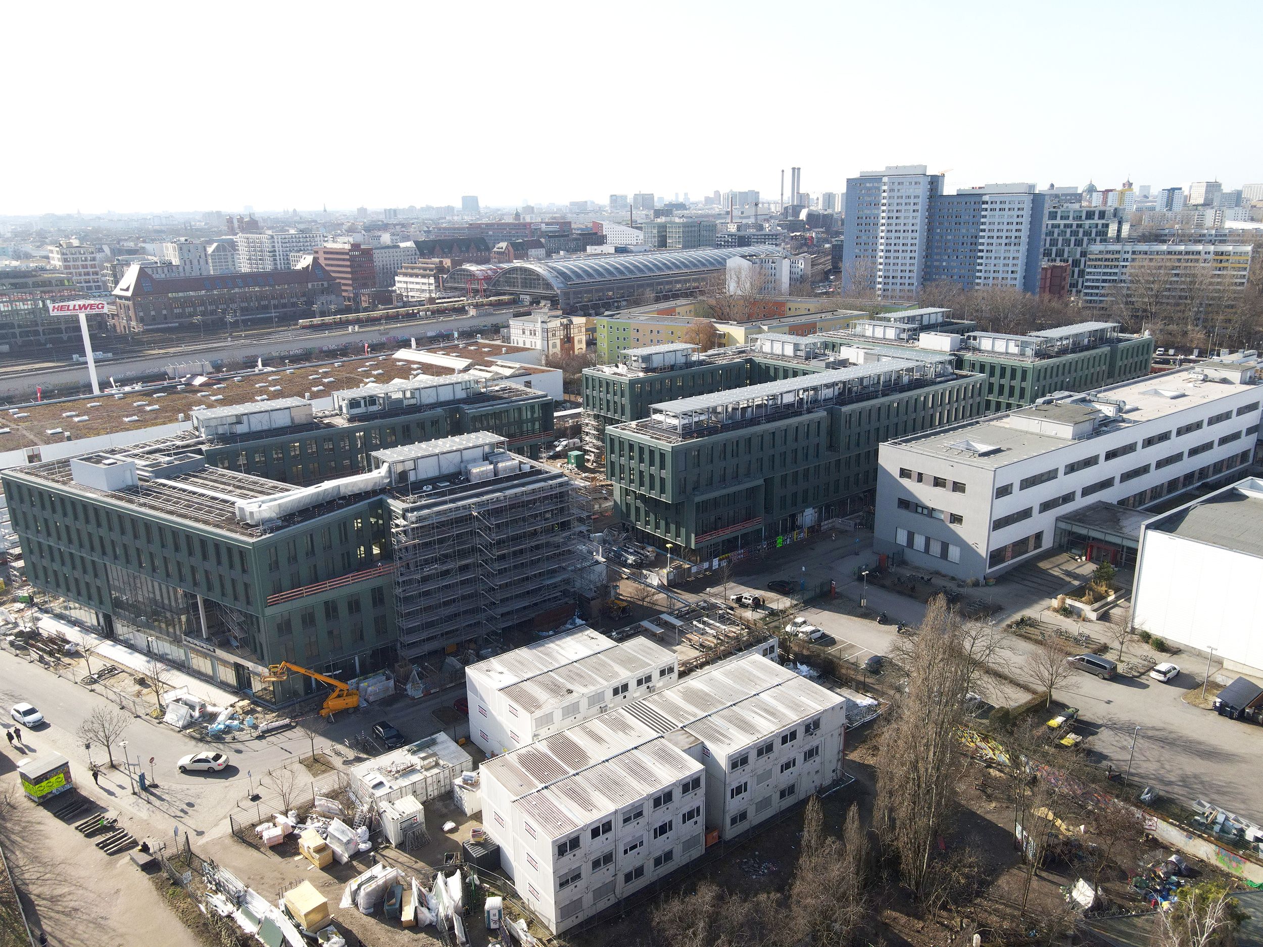 Baukräne über einer großen Baustelle mit mehrstöckigen Gerüsten unter klarem Himmel