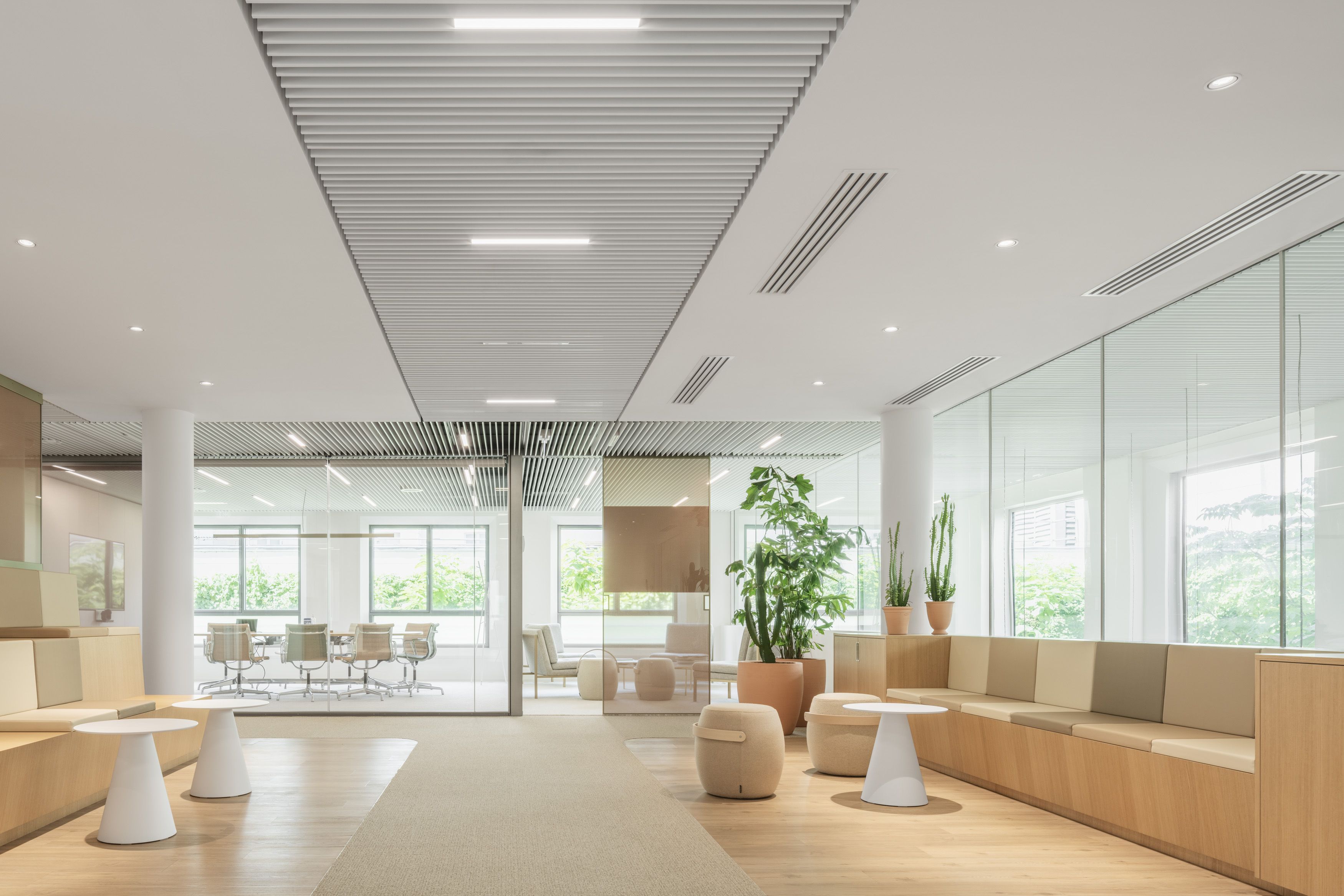 Moderne Büroumgebung mit Holz- und Glasakzenten, durch große Glastrennwände fällt der Blick in einen Konferenztisch.