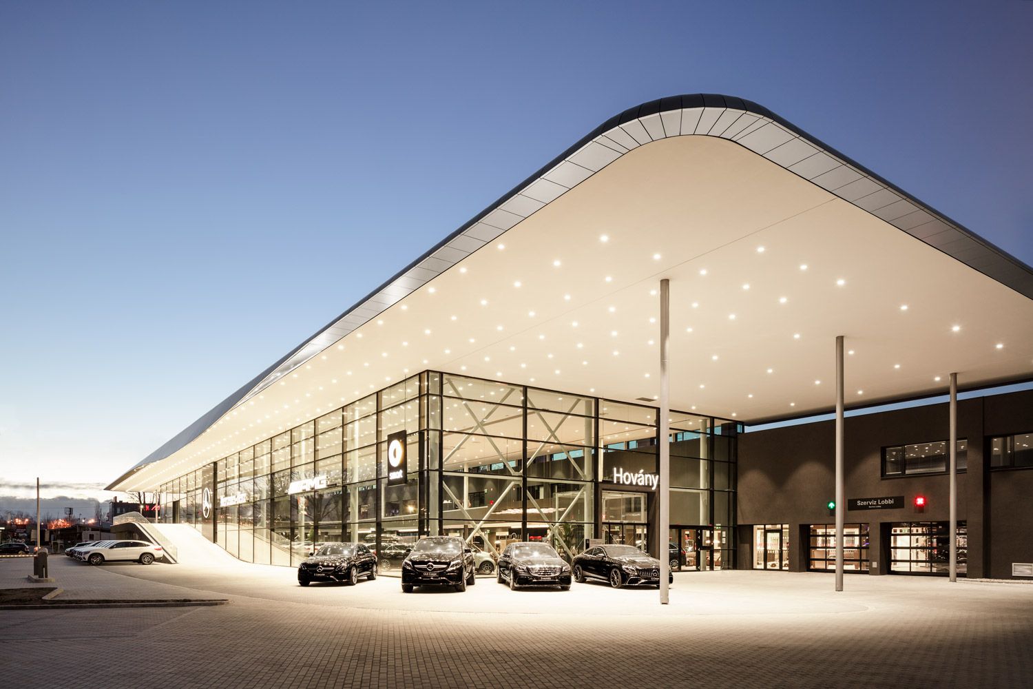Mercedes-Benz Autohaus mit mehreren geparkten Fahrzeugen vor Glasfassade und großem Mercedes-Stern-Logo