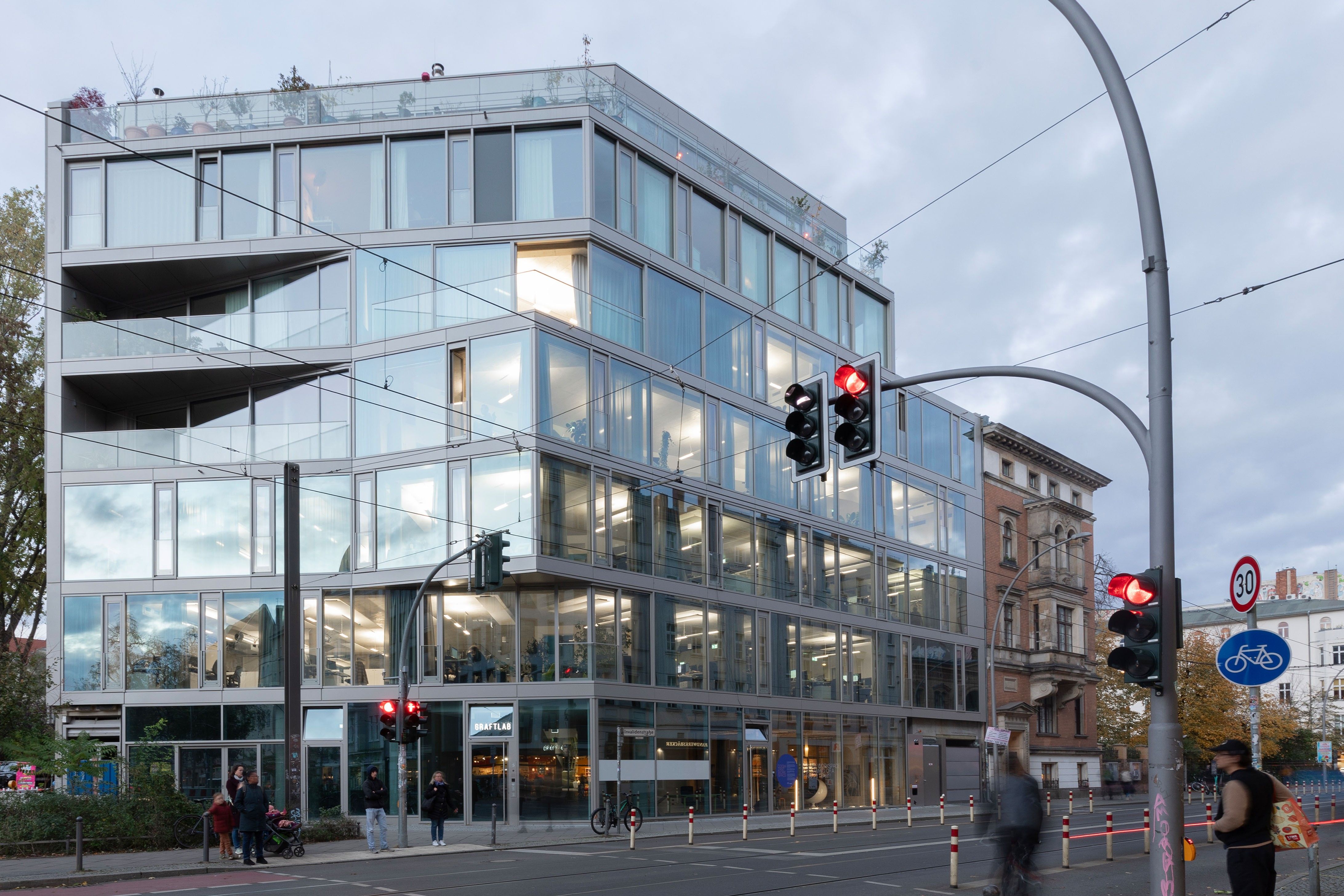 Modernes Glasgebäude, die Lichter sind an und man kann in das Gebäude hineinsehen