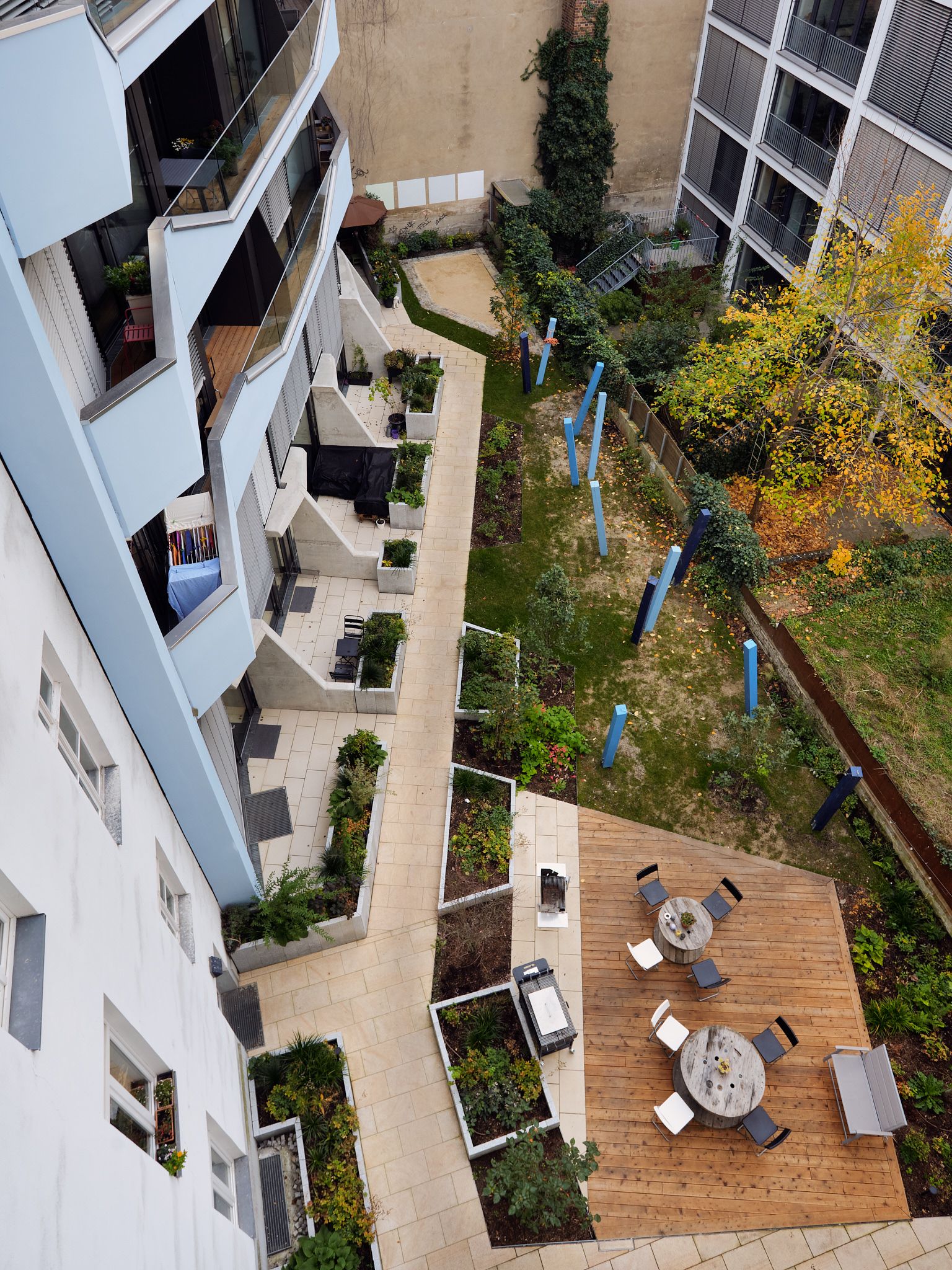 Aerial view of a residential courtyard with a wooden deck, bordered by modern apartment buildings.