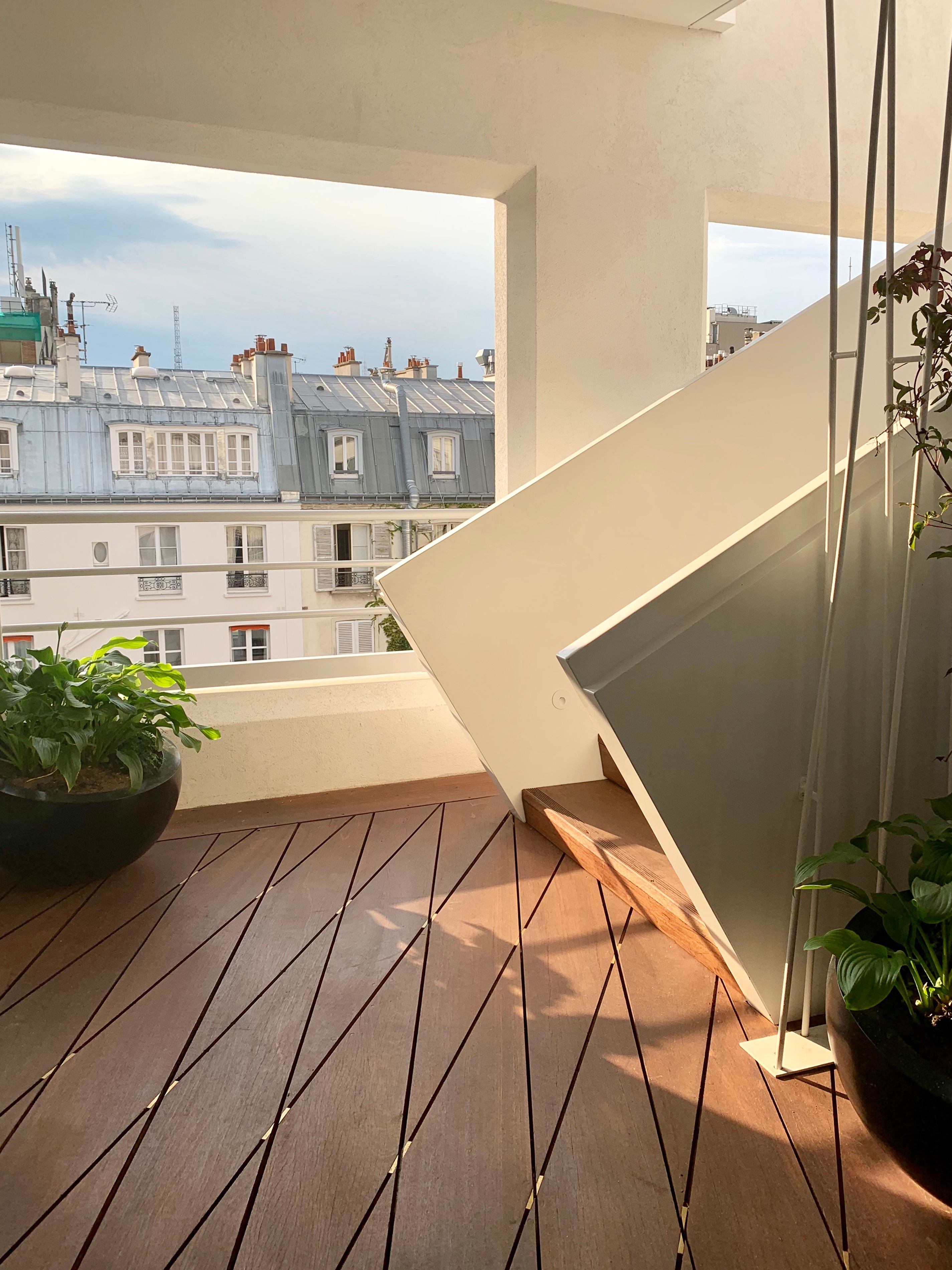 a patio in a Parisian city context showing a refined wooden terrace flooring and a staircase leading upstairs