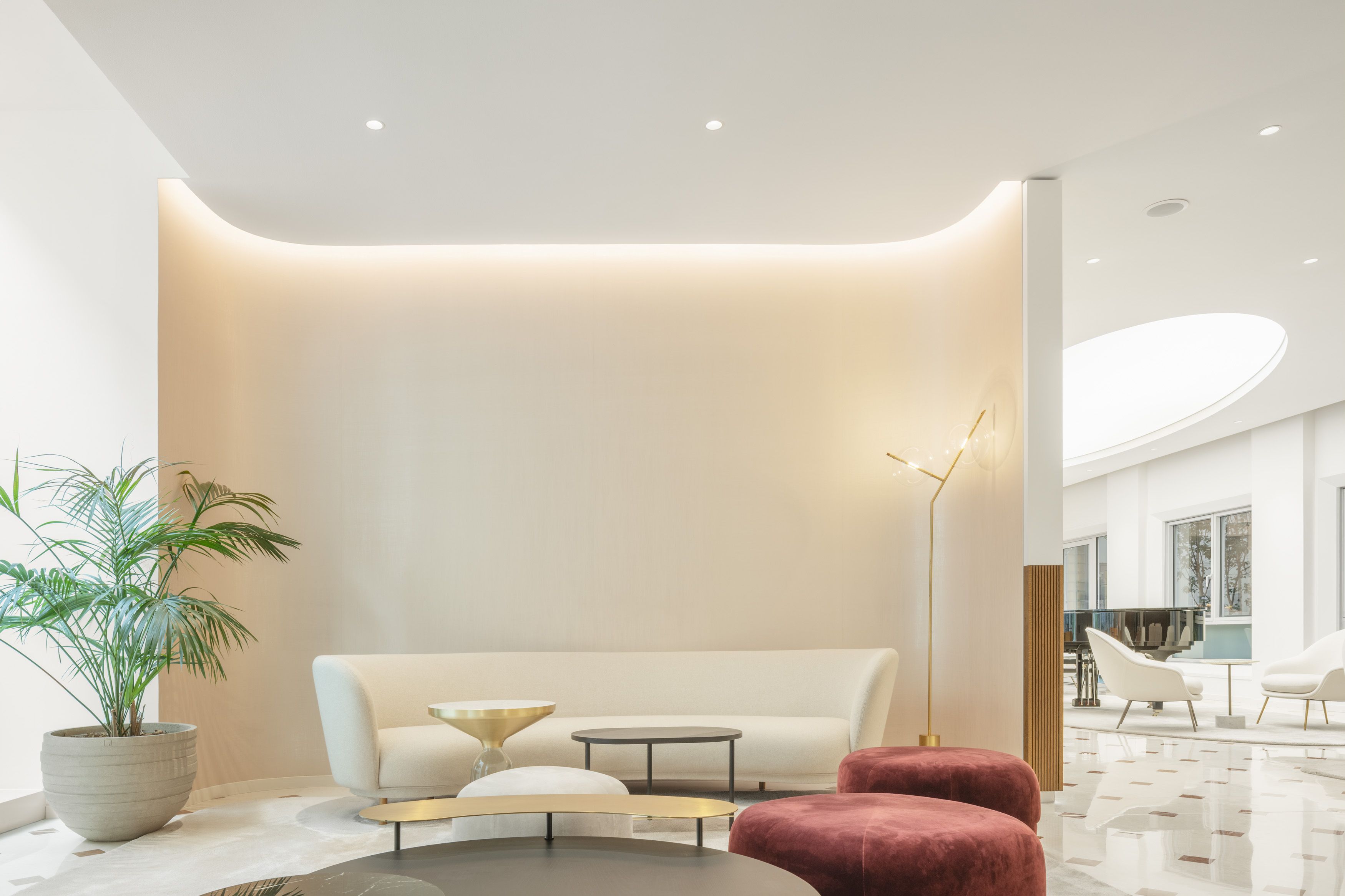 Elegant white interior with a slightly rounded and warm focus wall. Elegant and cosy furniture in front