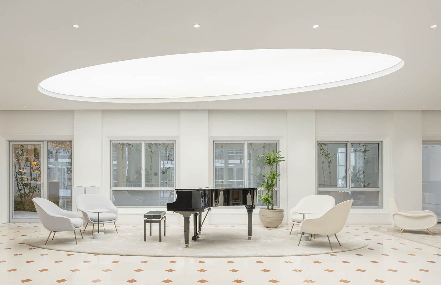 Modern white room with a black grand piano under an oval downlight