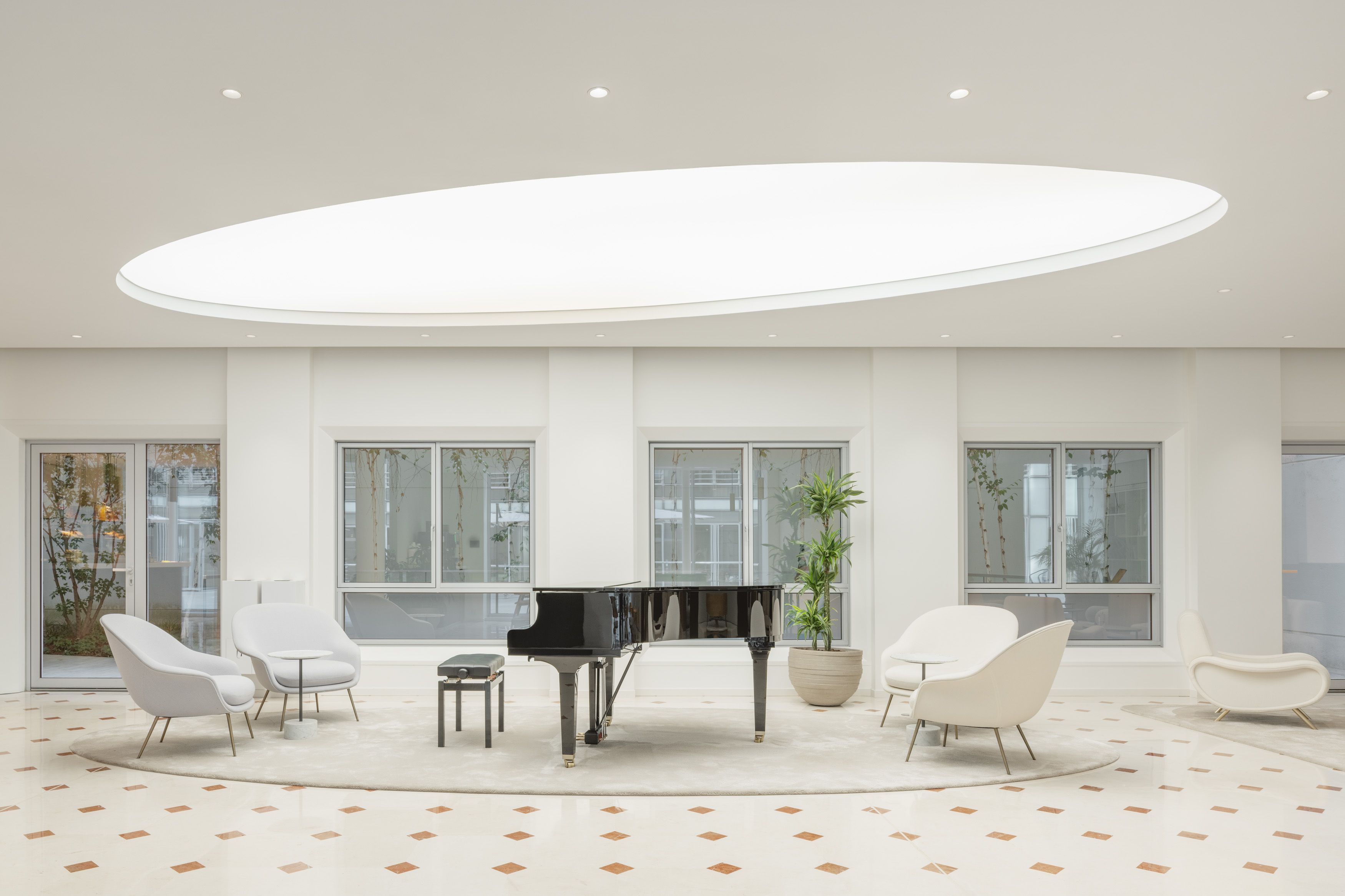Modern white room with a black grand piano under an oval downlight