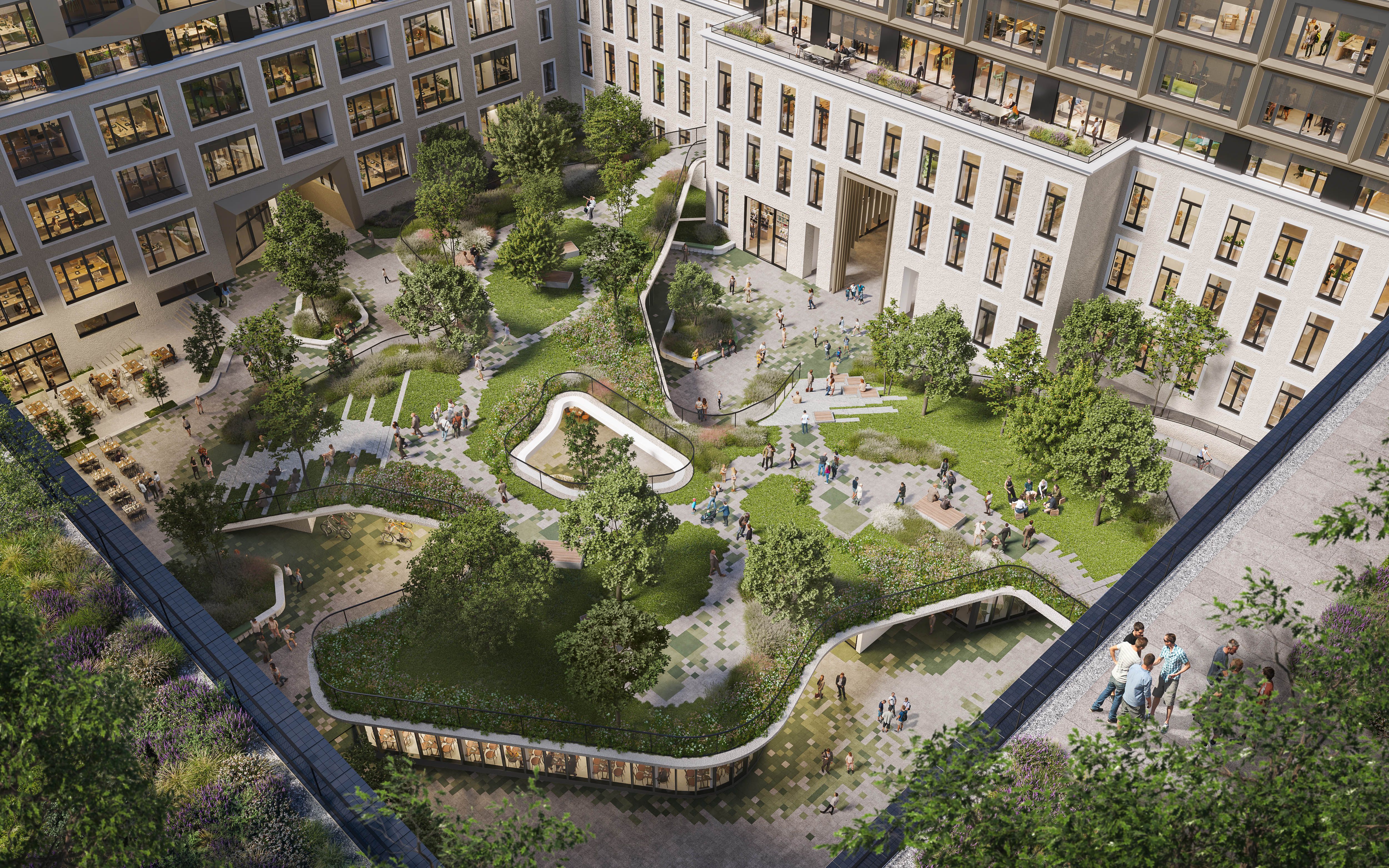A courtyard with winding paths, green lawns, trees, and seating areas surrounded by a multi-story building with large windows and people walking and sitting outdoors.
