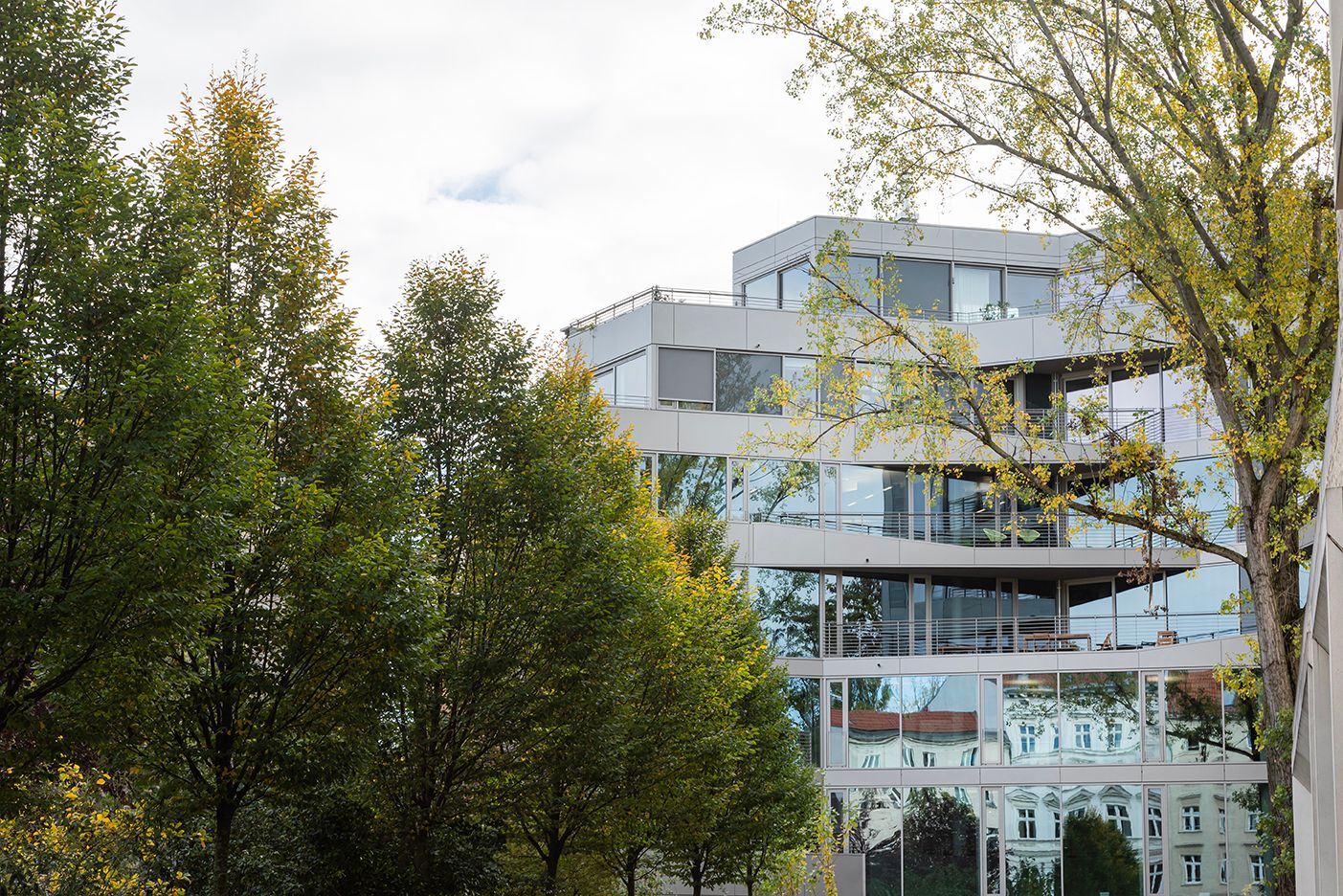 The neighbouring buildings reflect in the glass facade