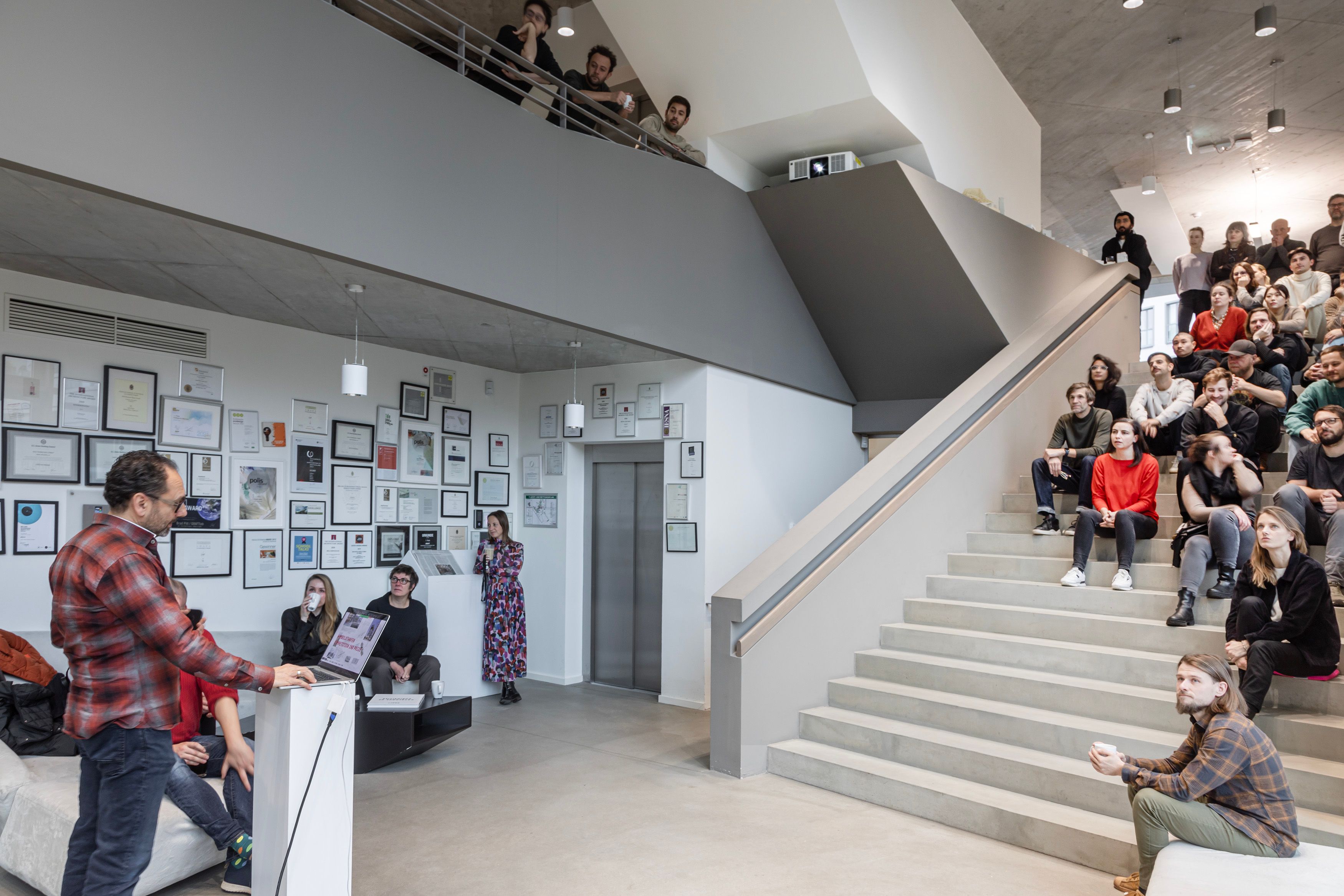 people sit on a bog staircase, listening to a lecturer