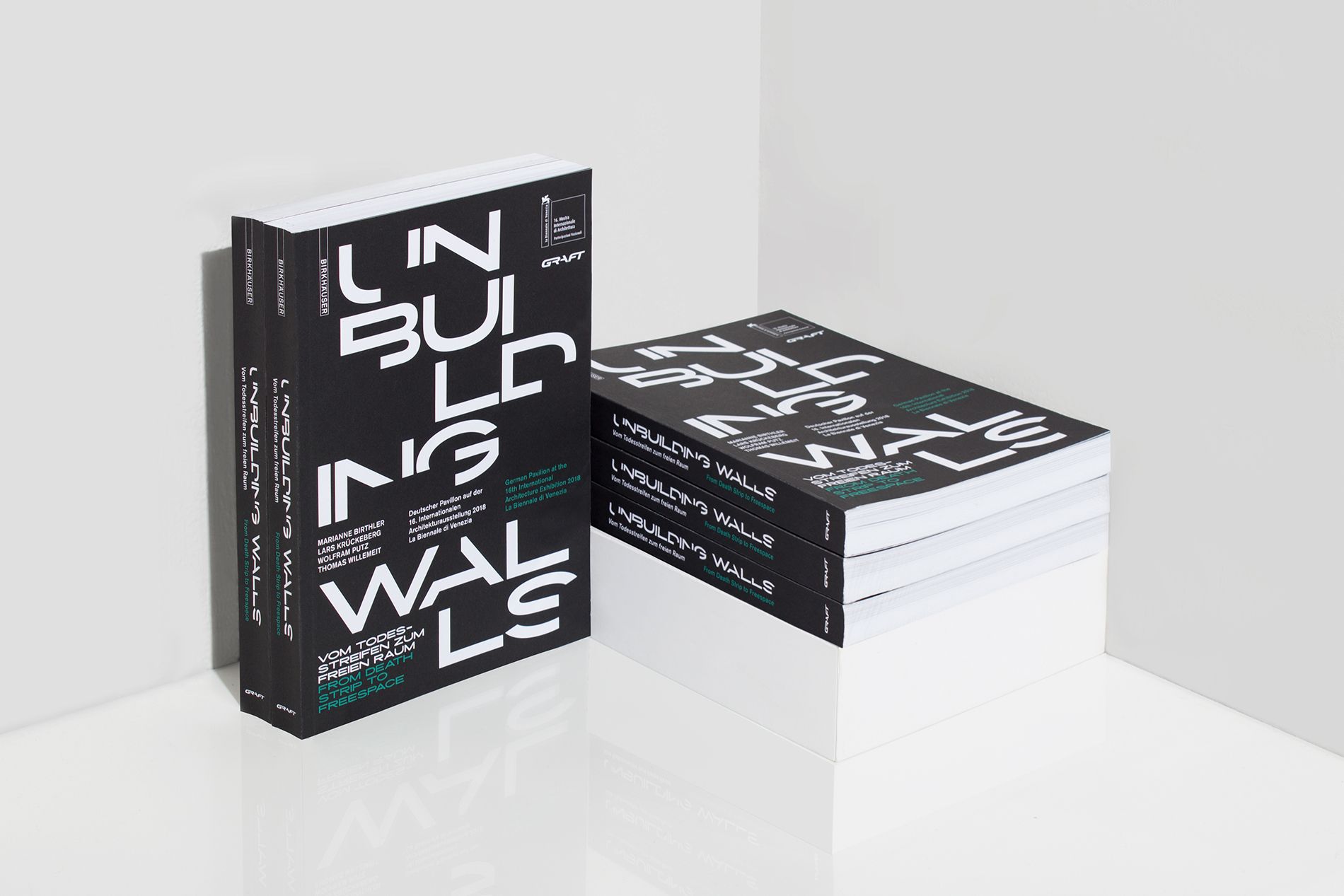 two book standing, three book in a stack, black with bold white letters on the cover