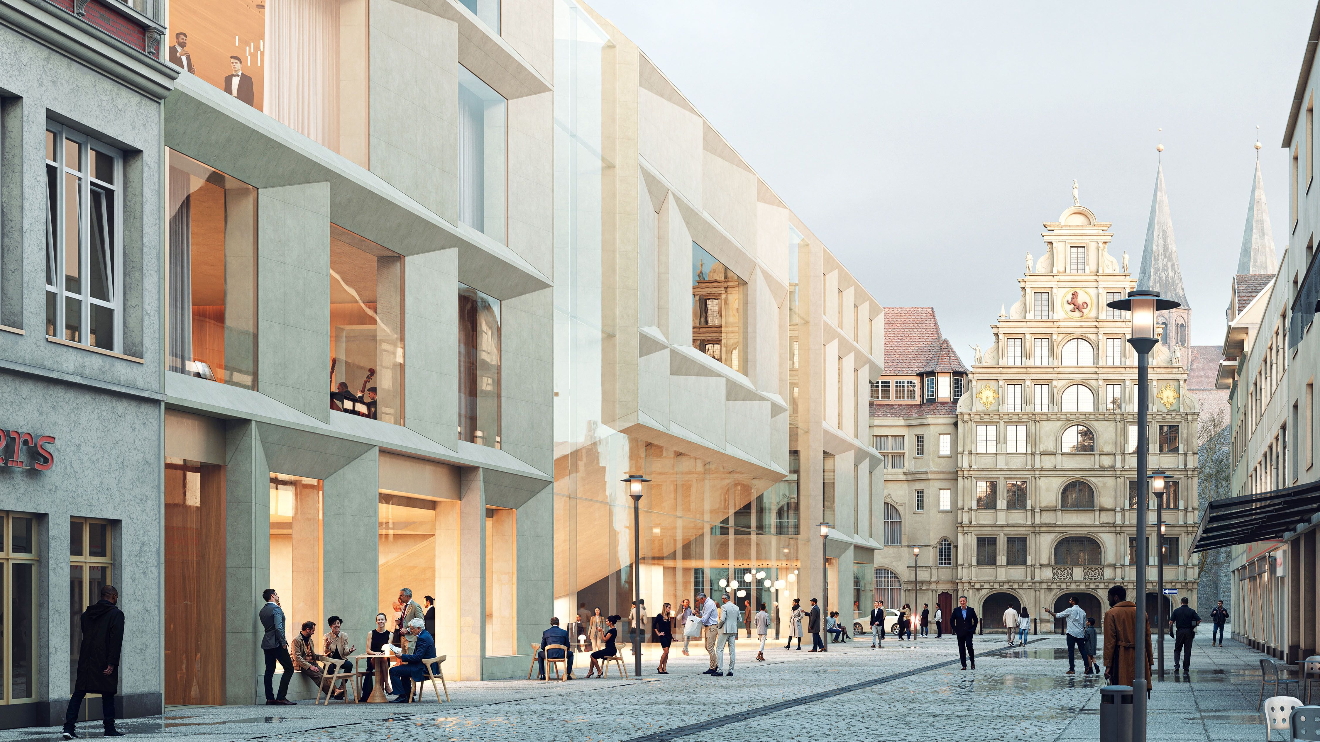 Modern concrete building with large windows and people sitting and walking on a street leading to historic multi-story building with ornate facade and spires in the background