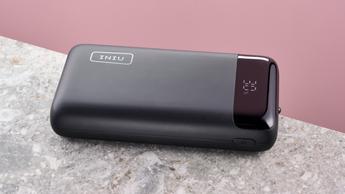 Iniu PD 22,5W 20.000mAh bærbar powerbank placeret på en stenoverflade med lyserød baggrund