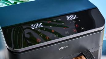 Uma fritadeira elétrica Cosori preta com duas cestas, janelas transparentes, luzes internas, grelha e espetos para churrasco