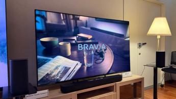 65-дюймовый телевизор Sony Bravia 5 на деревянной тумбе, на экране — сцена из фильма «Охотники за привидениями: Ледяное царство»
