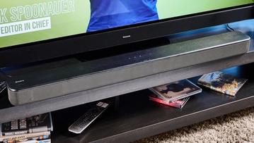 Eine Sony HT-S100F Soundbar mit Tasten oben und Fernbedienung, neben einem Panasonic Fernseher