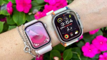 Zoom sur le poignet d'une personne portant l'Apple Watch Series 10 et Ultra 2 avec des fleurs roses en arrière-plan