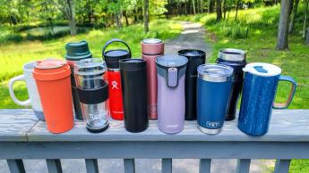 Una colección de las mejores tazas de viaje para café en una barandilla exterior