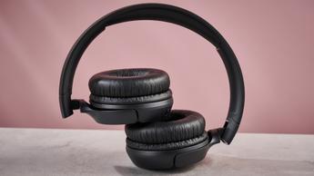 Fones de ouvido JBL Tune 510BT sem fio dobrados sobre um fundo rosa