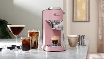 A máquina de espresso De'Longhi Dedica Duo na cor rosa sobre uma bancada de cozinha com bebidas à base de café
